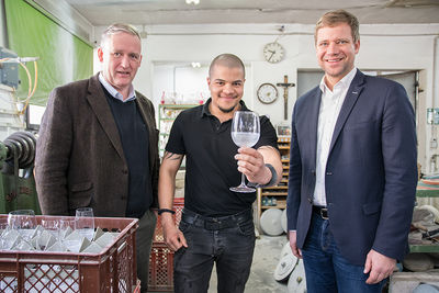 Geschäftsführer Max von Schnurbein (v.l.) und Mitarbeiter Nathan Tummings mit Bezirkstagspräsident Dr. Olaf Heinrich.